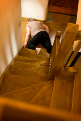 Seniorin liegt gestürzt am Fuß einer Treppe